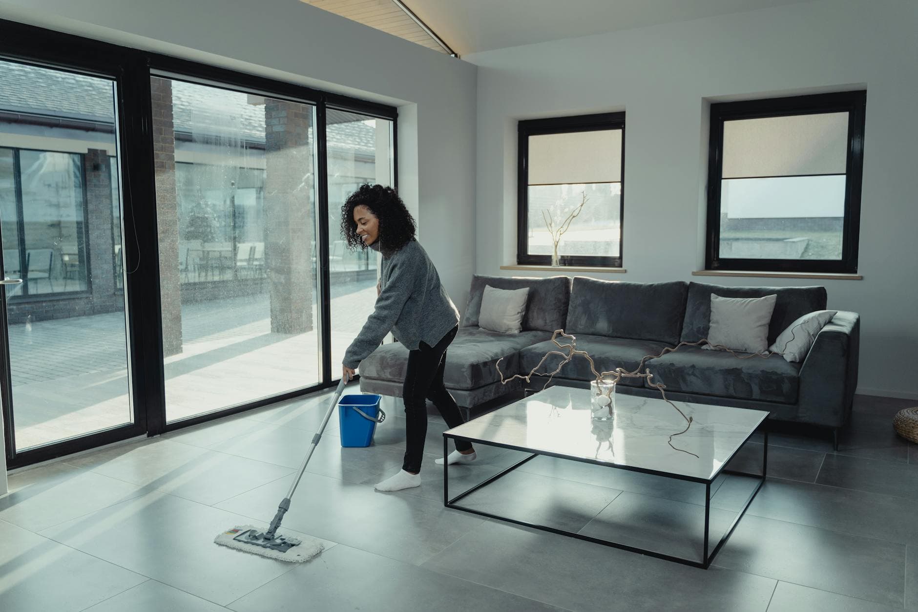 House cleaner mopping a bright, modern NYC apartment with large windows — Regular Apartment Cleaning in Arverne, Queens