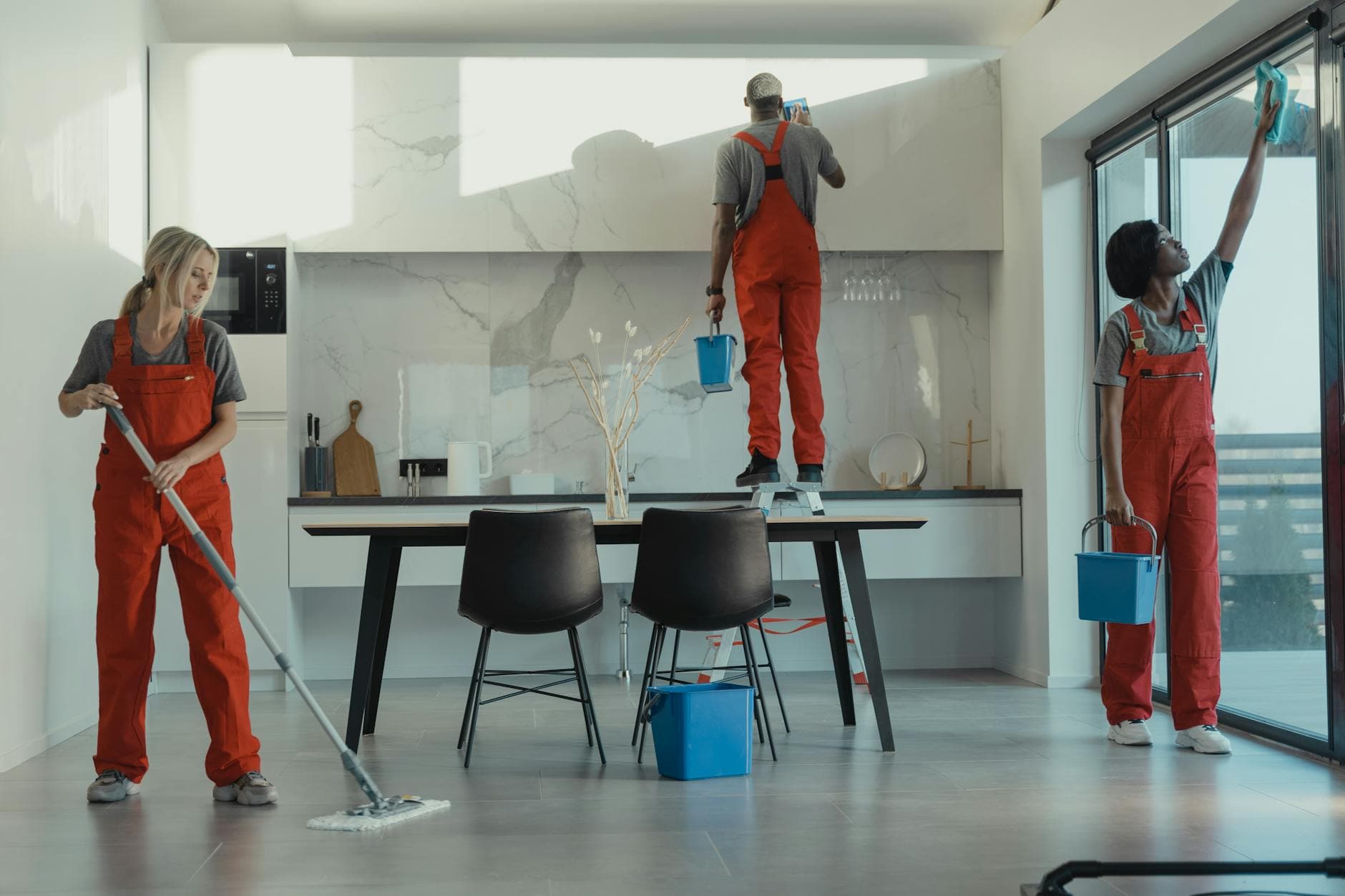 Your Business cleaning crew in red uniforms mopping and wiping glass in a New York dining room — Office Cleaning in Douglaston, Queens