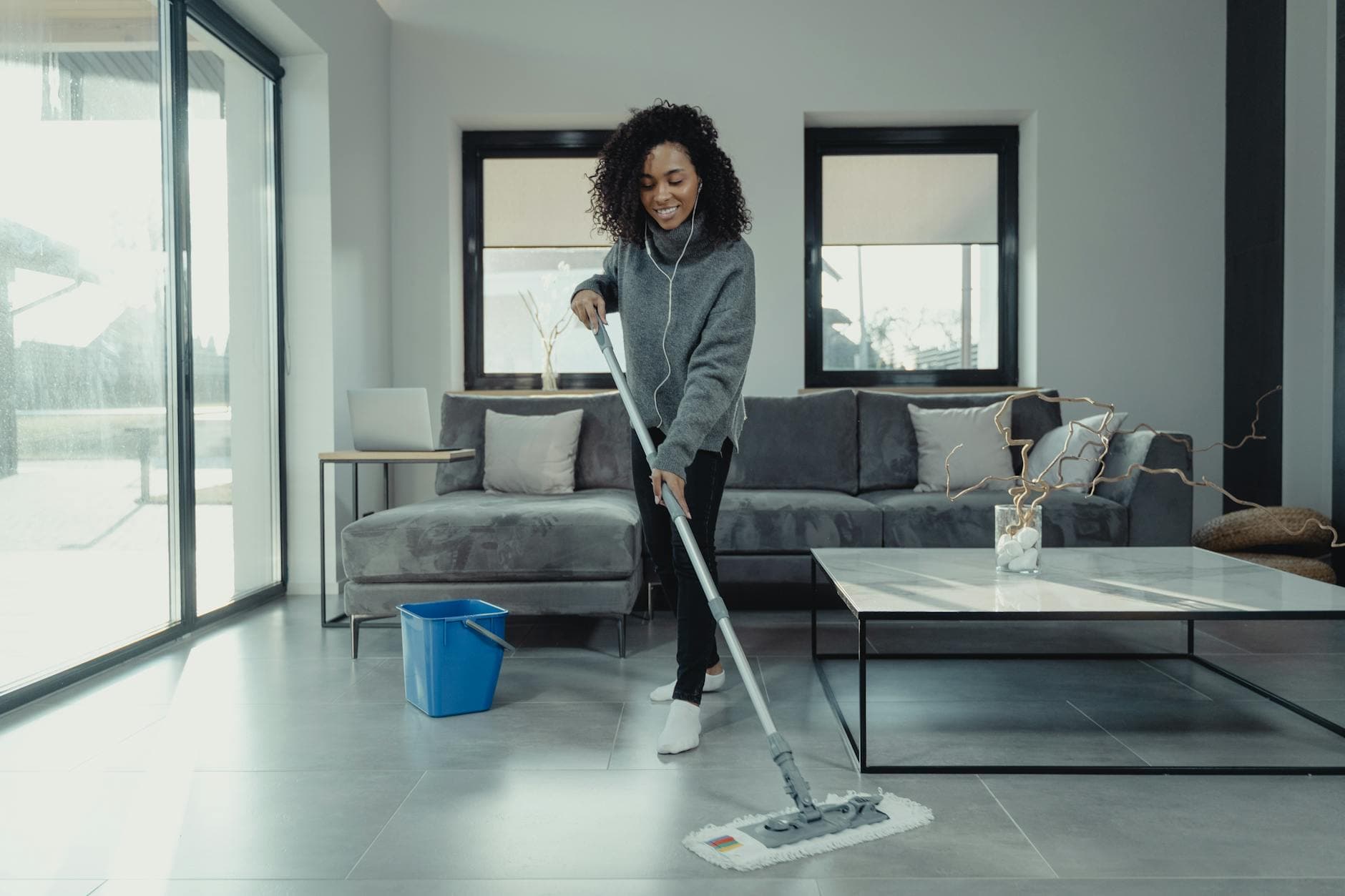 A maid from Your Business mopping a tiled floor in a cozy New York City apartment — cleaning services in Flushing, Queens