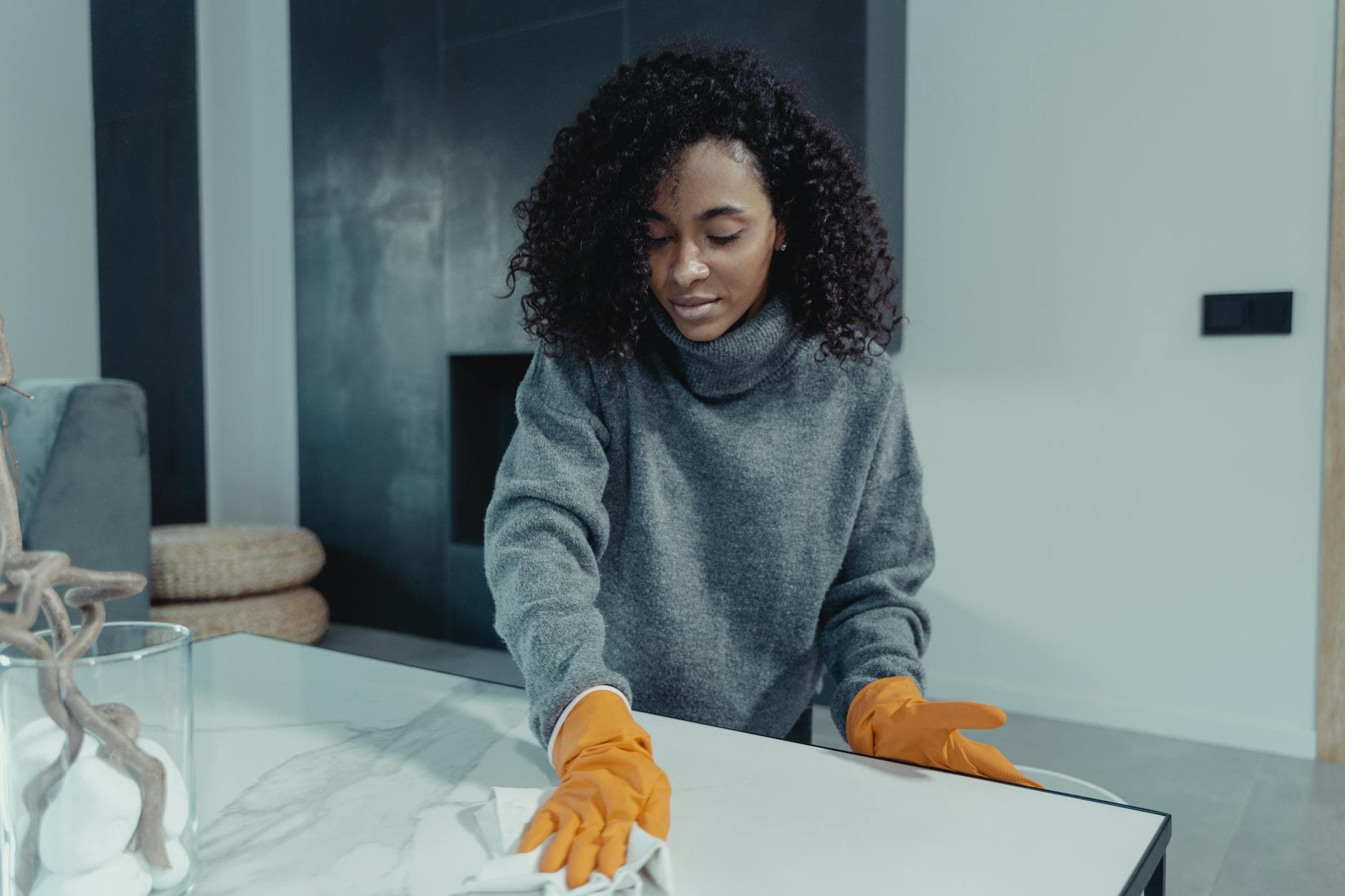 A professional cleaner wearing gloves wiping a coffee table in a modern Manhattan living room — cleaning services in Annadale, Staten Island